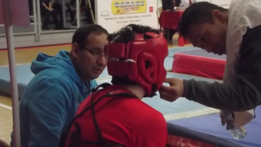 a man wearing a red boxing glove while talking to another person in front of an open box