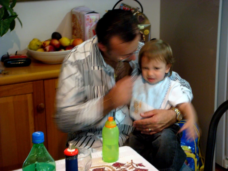 a man holds a child as they sit near the counter