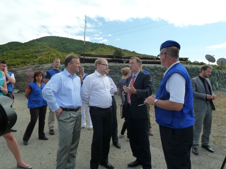 the men are standing together talking on a road