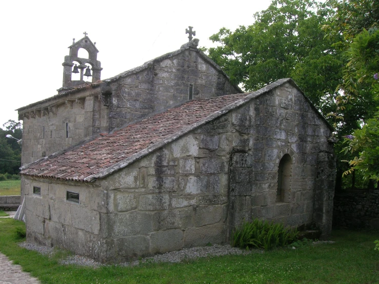an old church with a bell in a garden
