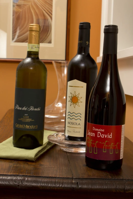 three bottles on a table with one empty glass