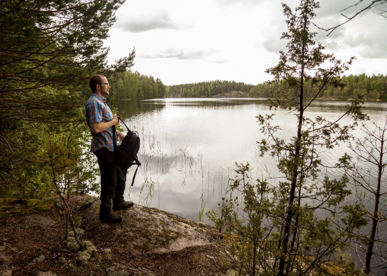 man with a backpack standing on a cliff overlooking a large body of water