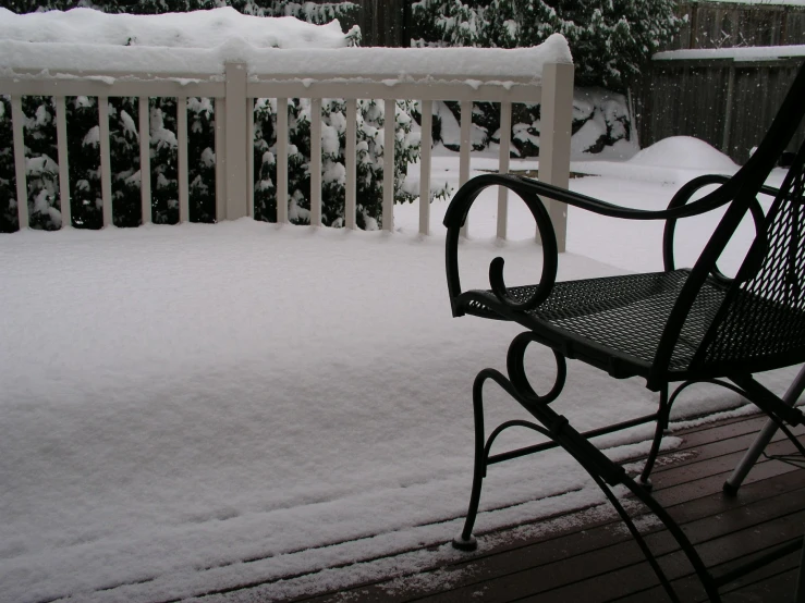 a bench sits on the deck while covered in snow