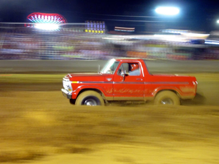 an old pickup truck driving around a dirt track