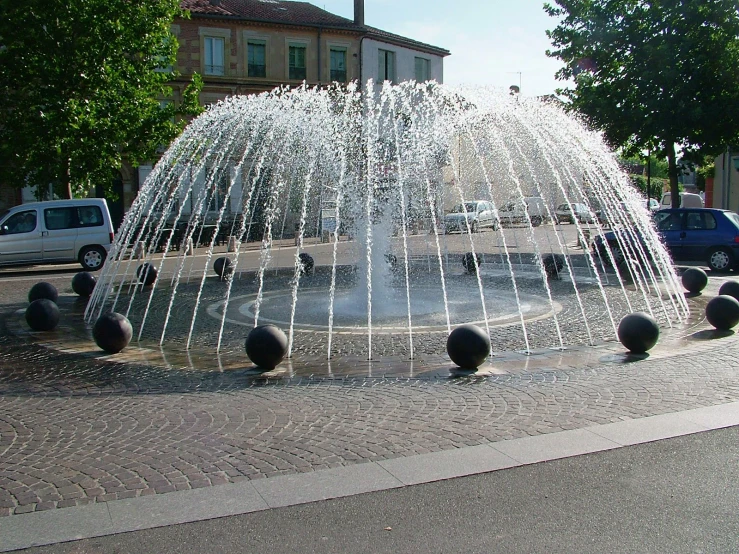 a large water fountain in front of cars parked on the street