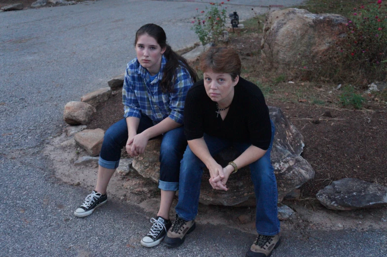 two people are sitting on a rock outside