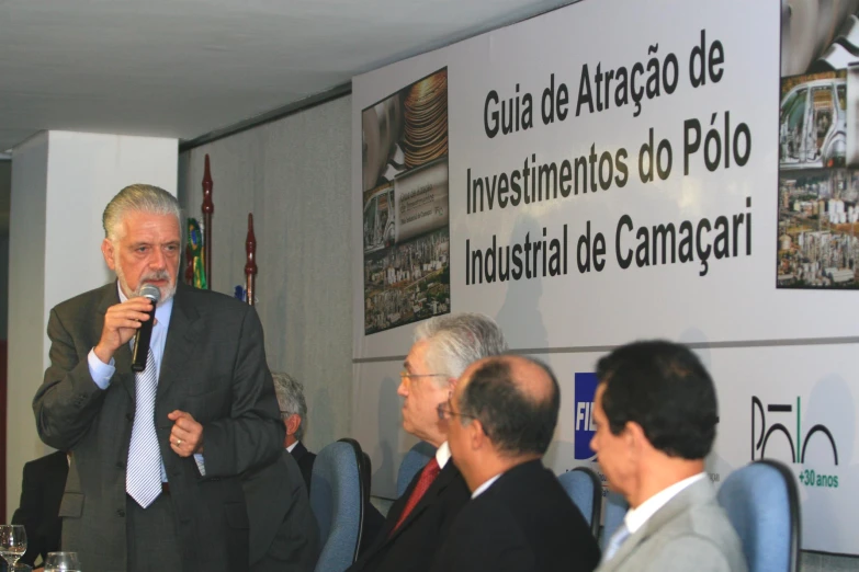 a man speaks into the microphone in front of some people