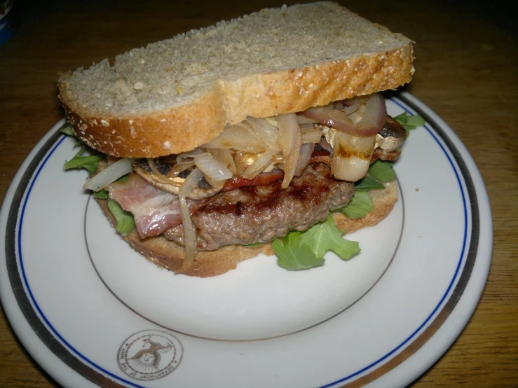 a toasted sandwich with meat, onion and lettuce on it