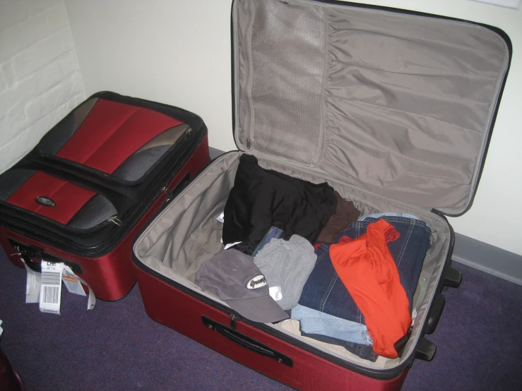 suitcase opened and packed with clothes and gloves