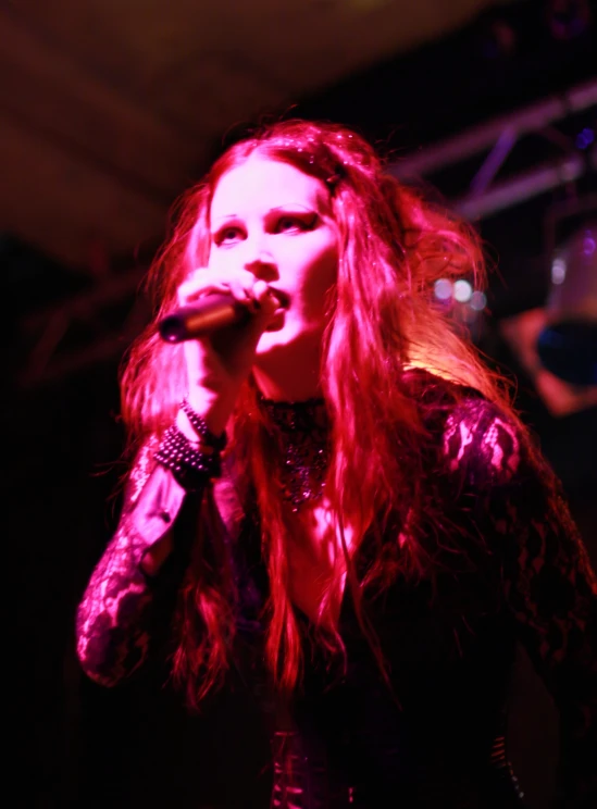 a female with long red hair is holding a microphone