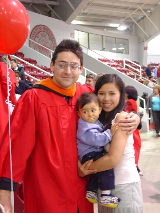 an adult posing with a child while dressed as a graduate