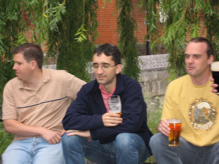 a group of men sitting down while holding beers