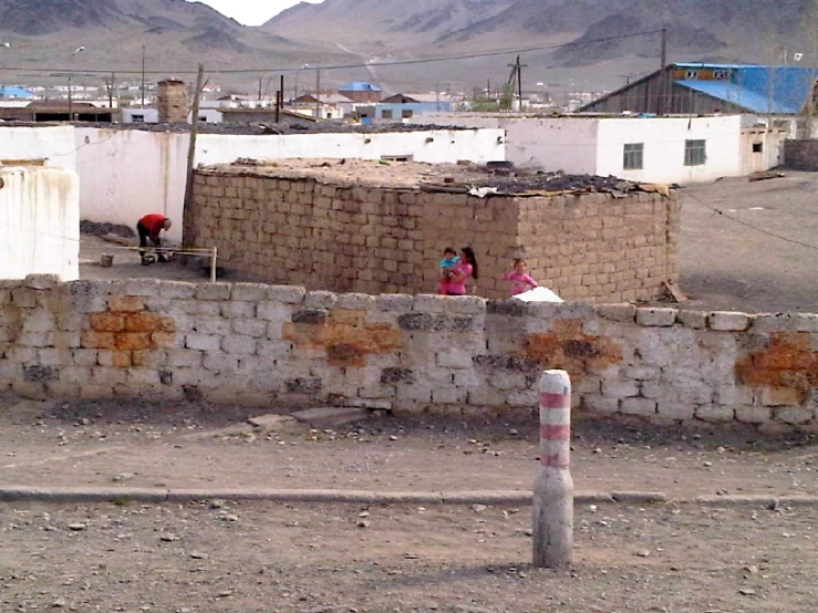 two people walking by the city wall near some mountains