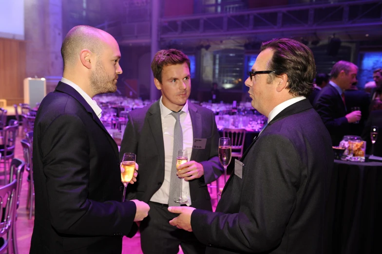 three men standing and talking at a convention