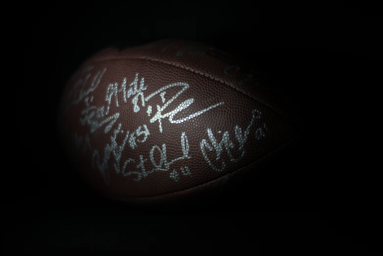 the signed football is sitting on the black surface