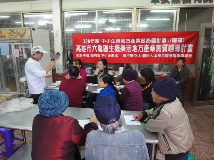 a group of people at a counter with a chinese sign