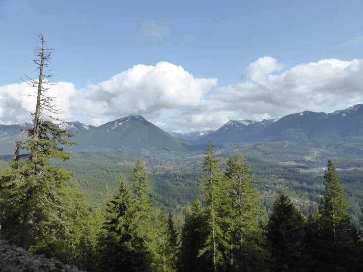 a landscape view of mountains, trees, and a blue sky