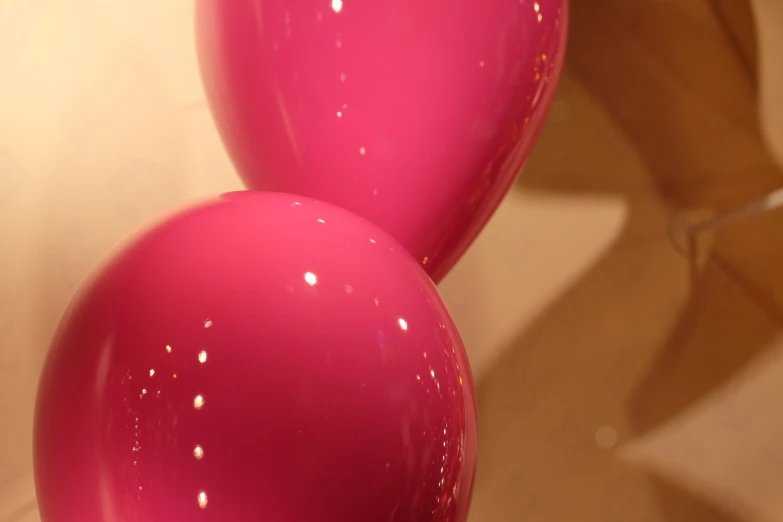 pink balloons are lined up in front of a brown wall