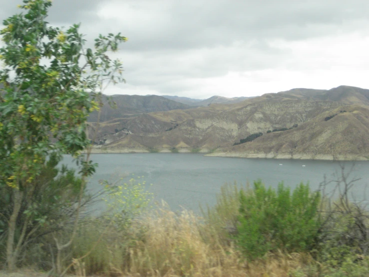 a lake is surrounded by mountains with green plants