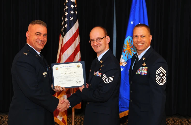 military members hold a plaque while posing for a po