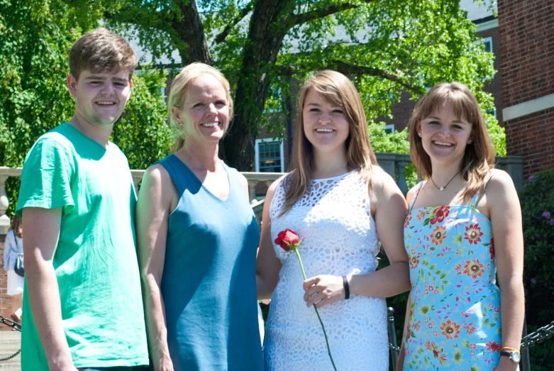 three adults and two children standing together outside of a building