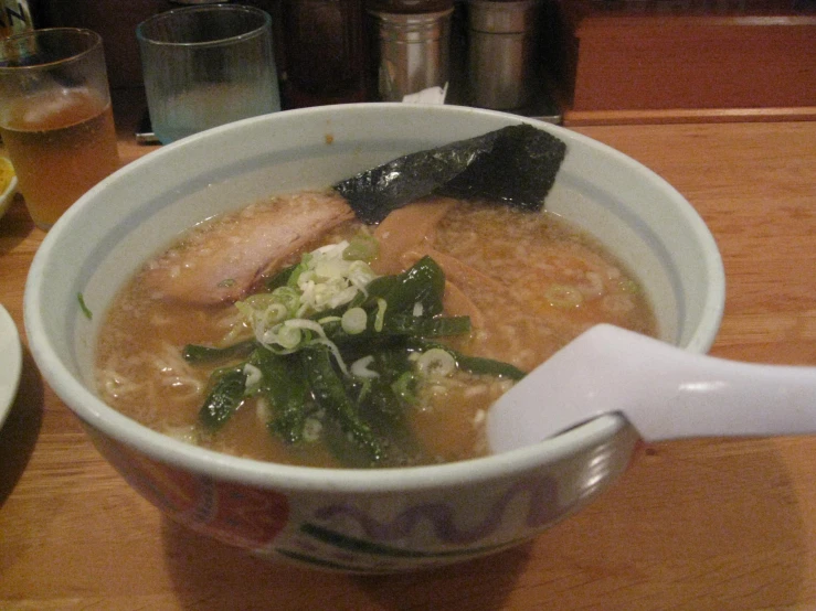 a bowl of soup with greens on the side