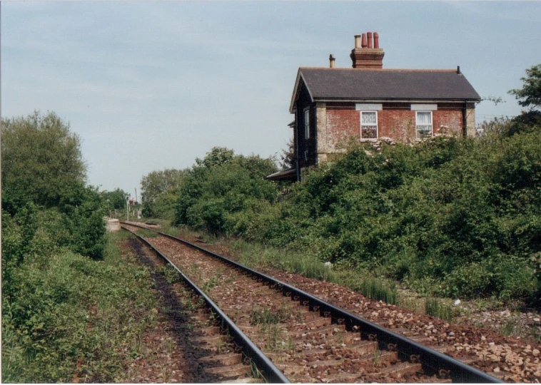 the railroad tracks go past a brick building with windows