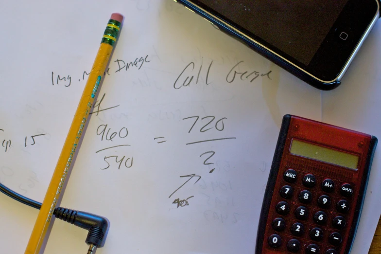 a pencil sitting next to a calculator and a phone on a table