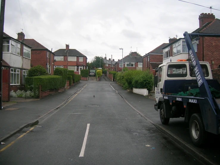 a tow truck sits in the middle of a quiet residential street