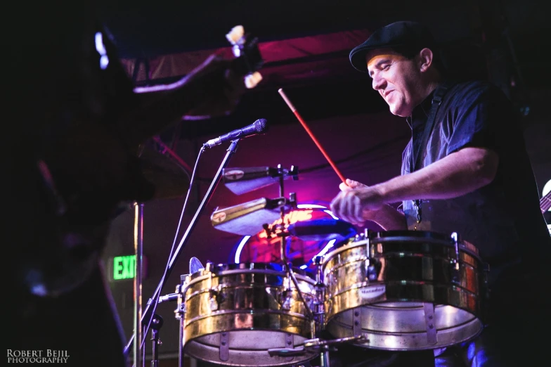 a man standing behind a drum set on a stage