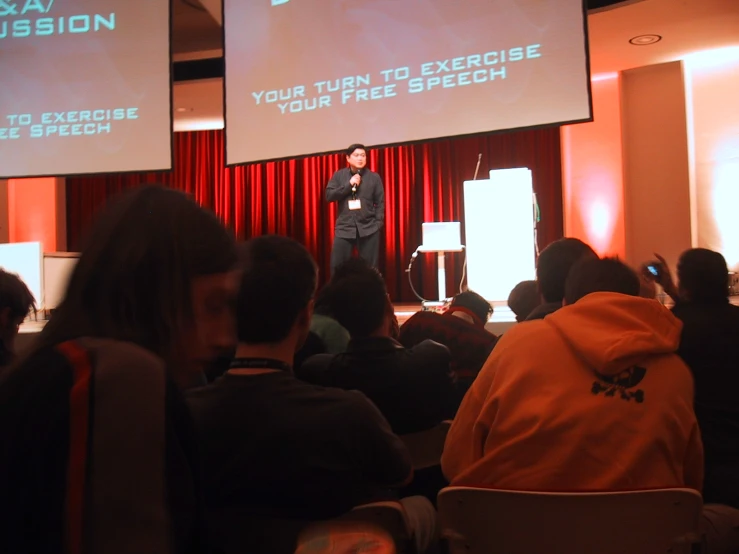 a person is giving a talk in front of a crowd