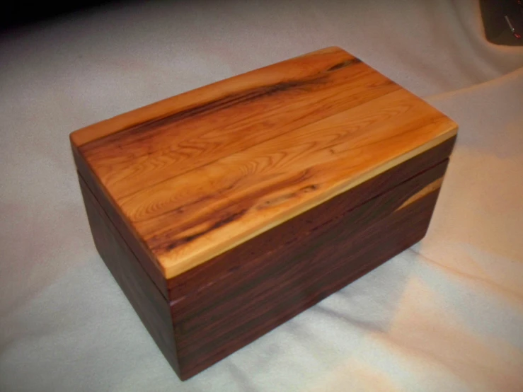 a square wooden box sitting on top of a white sheet