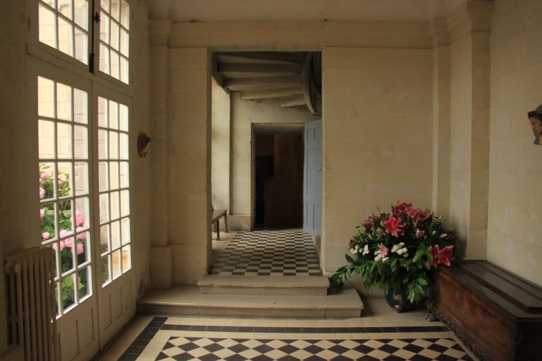 the entrance hall has an area rug, wooden bench, windows, and a black and white checkered floor