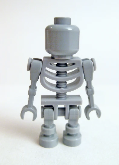 a grey plastic toy is standing up on a white surface