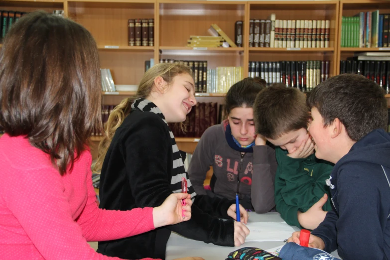 children sit around a table with a notebook and pens