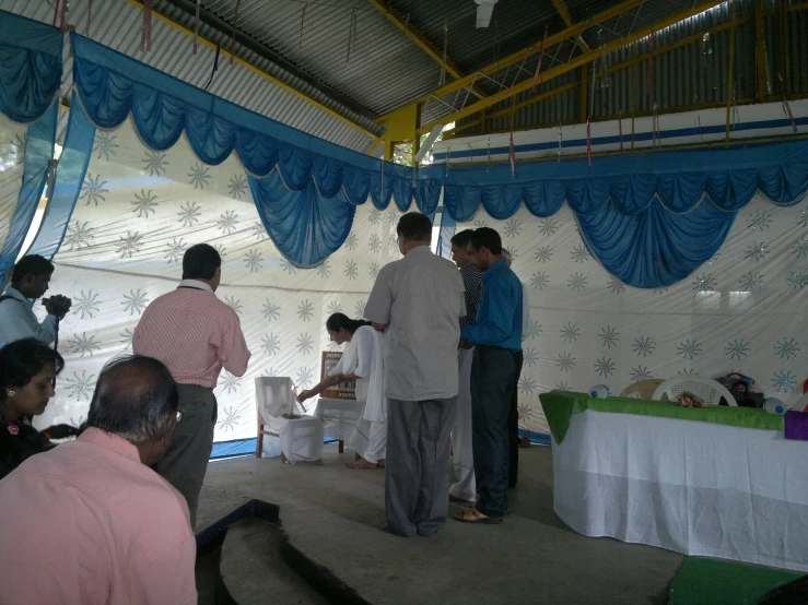 several people stand in an open tent with curtains