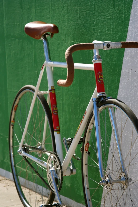a white bicycle leans against a green wall