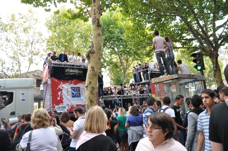 a large group of people in a crowd on top of two double decker buses