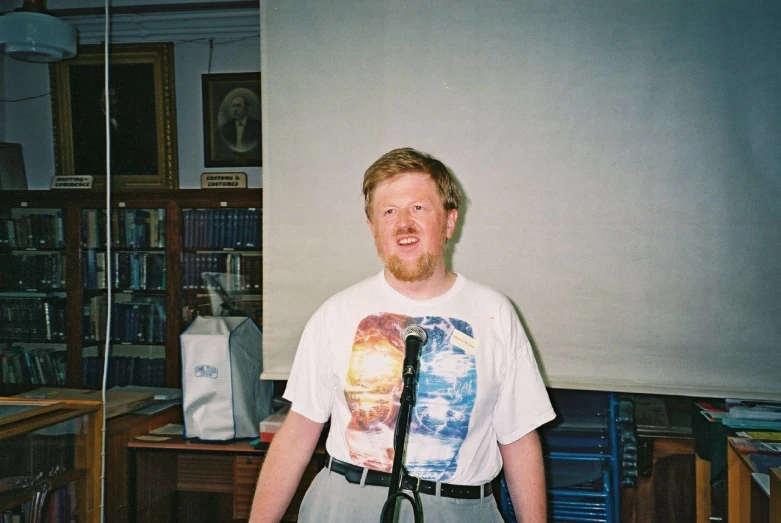 a young man smiling as he poses in front of the microphone