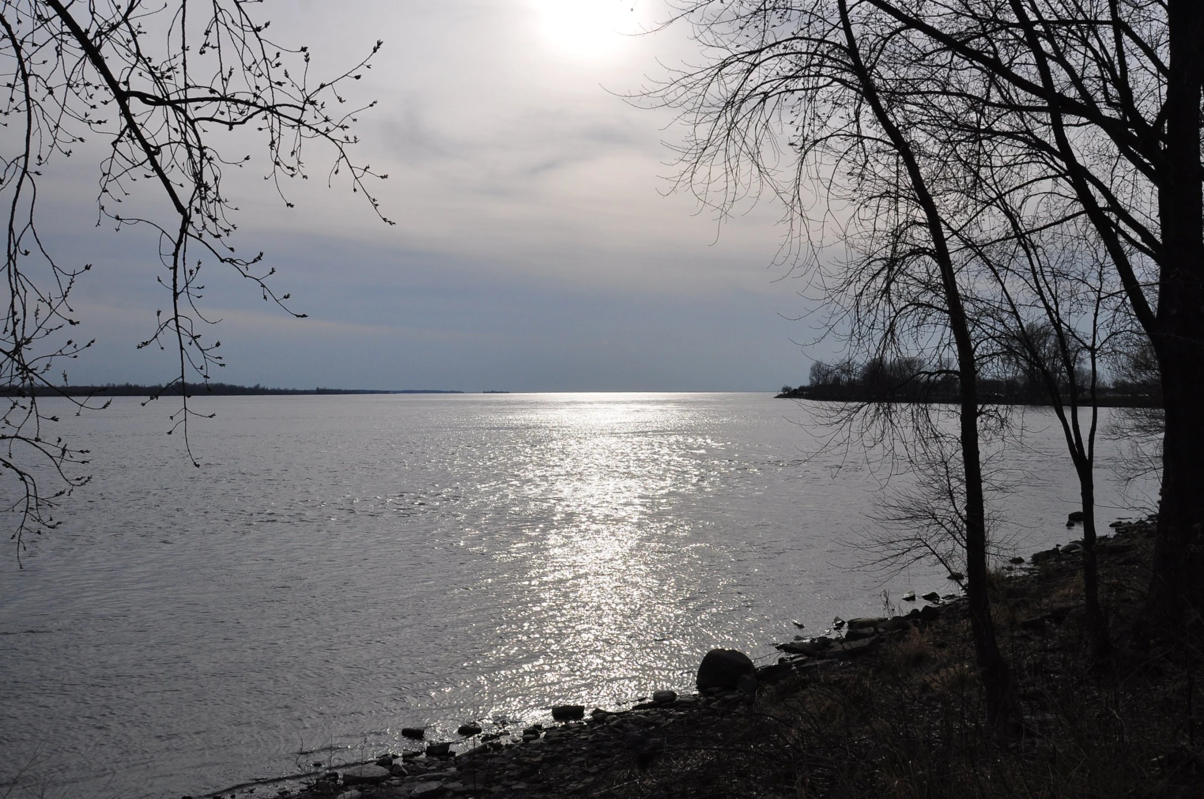 the sun is shining over a calm body of water