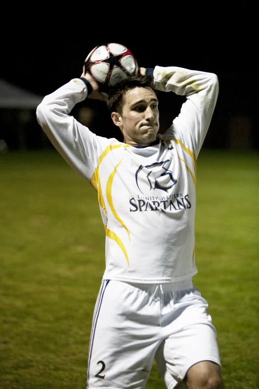 a man in a white uniform holding up his ball in the air