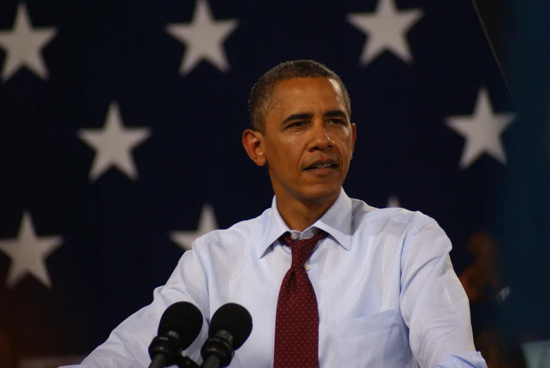 a close up of a person at a microphone in front of an american flag