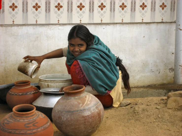 a woman that is kneeling down near some pottery