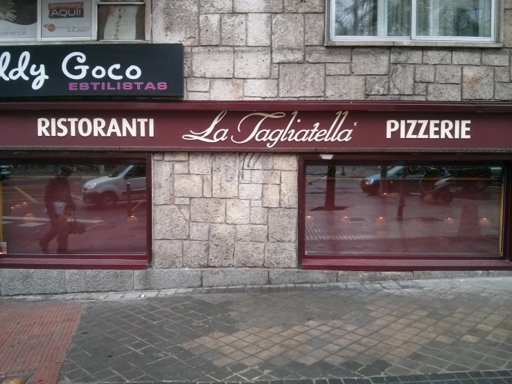 an italian pizza shop is closed and some people are walking by