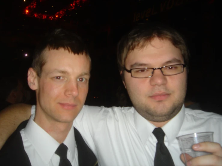 two people standing close together while one holds onto the glass