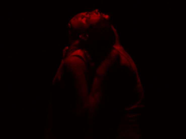 a man and a woman kissing against a dark background