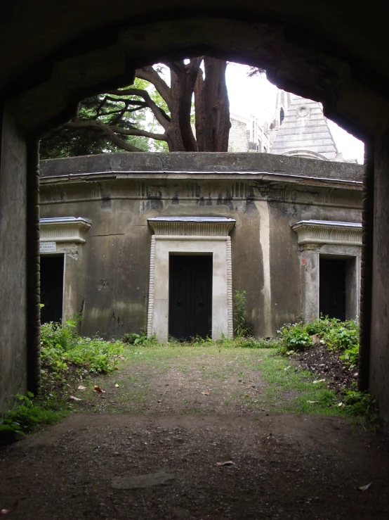 an old, abandoned, grey building in the woods with graffiti on it