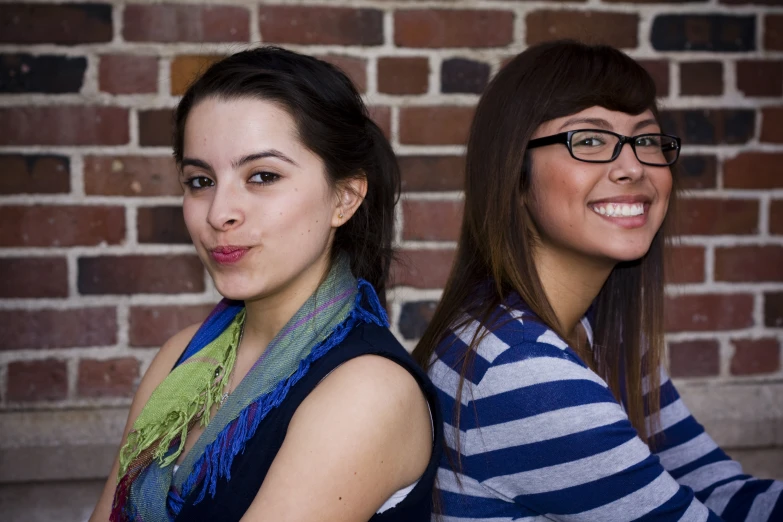 two young women pose with their arms around each other