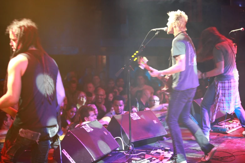 three men are standing on stage with microphones in their hand