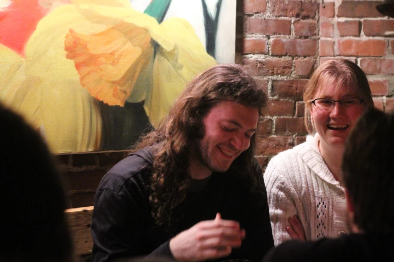 two men laugh at each other while at a bar